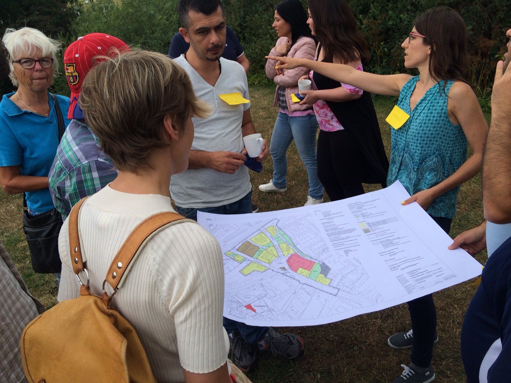 Bild på människor som står i ring och håller en ritning