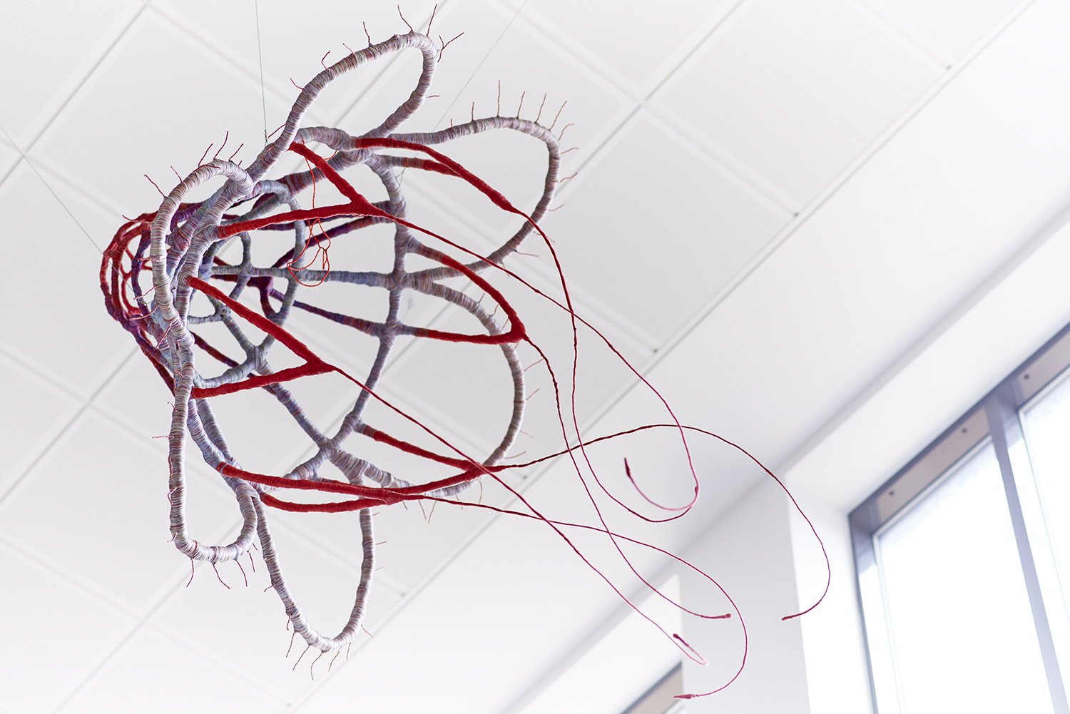 A sculpture of wires in red and grey silk.