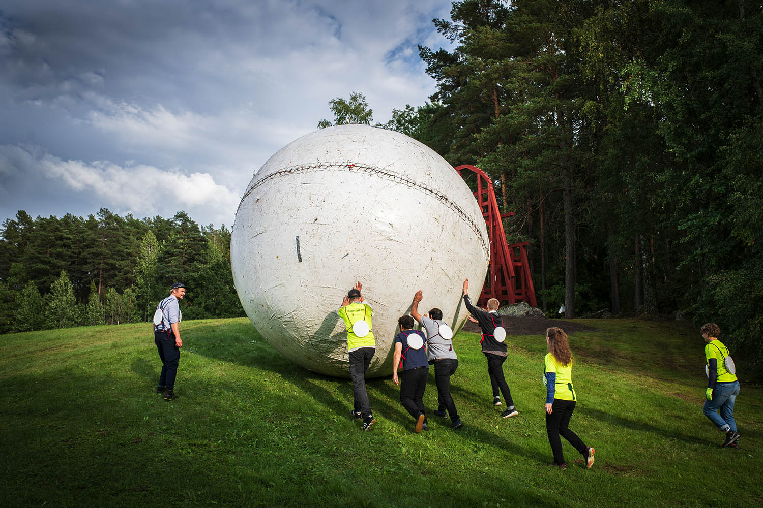 Människor rullar en stor boll på ett fält