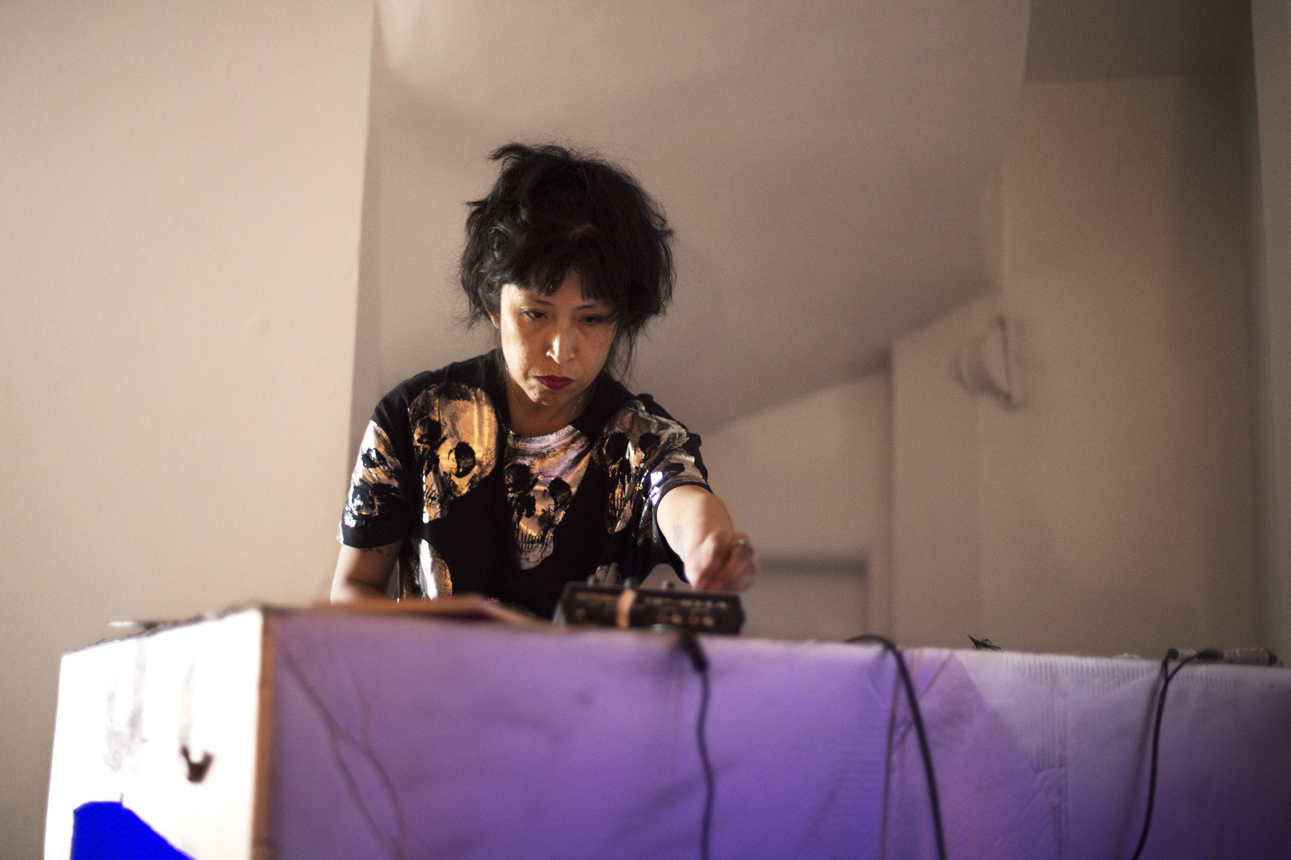 En kvinna står vid ett bord och verkar skruva på knappar. 