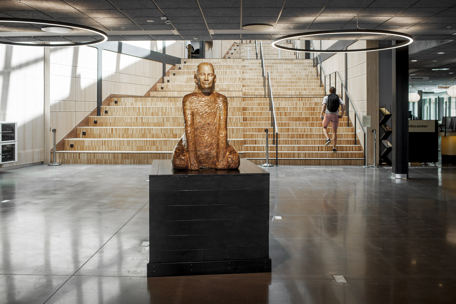 I en glänta i skogen, bland skir grönska, går människor i ett konstverk