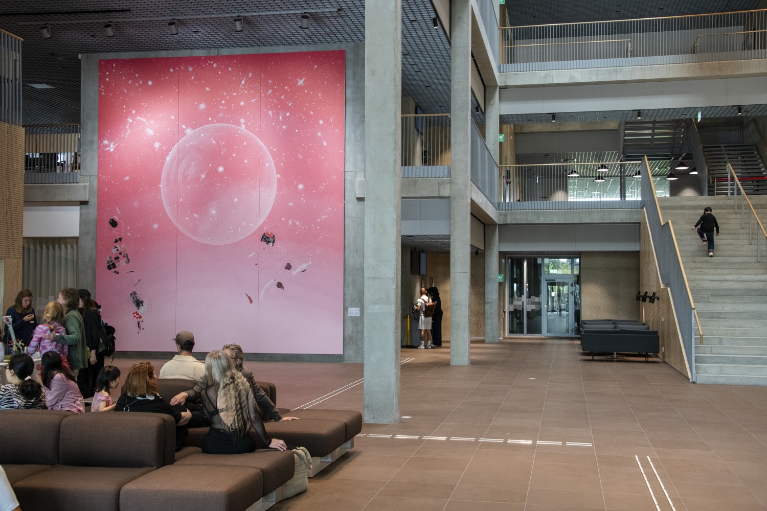 Stor målning i rosa toner placerad i ett rum med mycket volym.