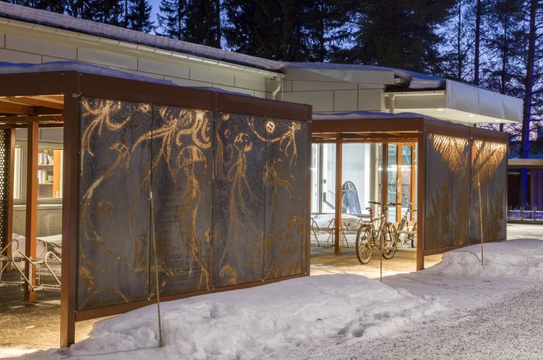 Cykelställ i skuren rostig plåt som lyser i vintermörkret