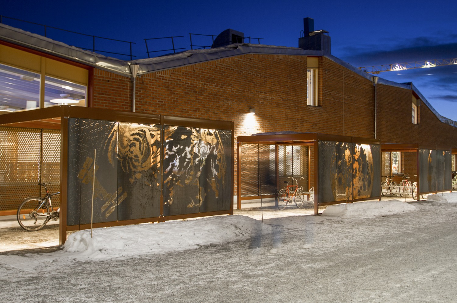 Cykelställ i skuren rostig plåt som lyser i vintermörkret