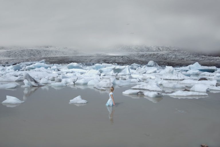 Uppklädd kvinna är i vattnet framför isflak
