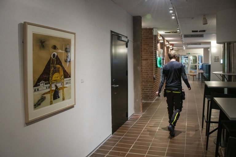 En man går längs en korridor med en målning på väggen