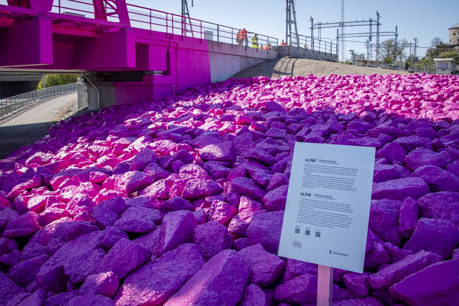 En rosa bro med en skylt framför sig.